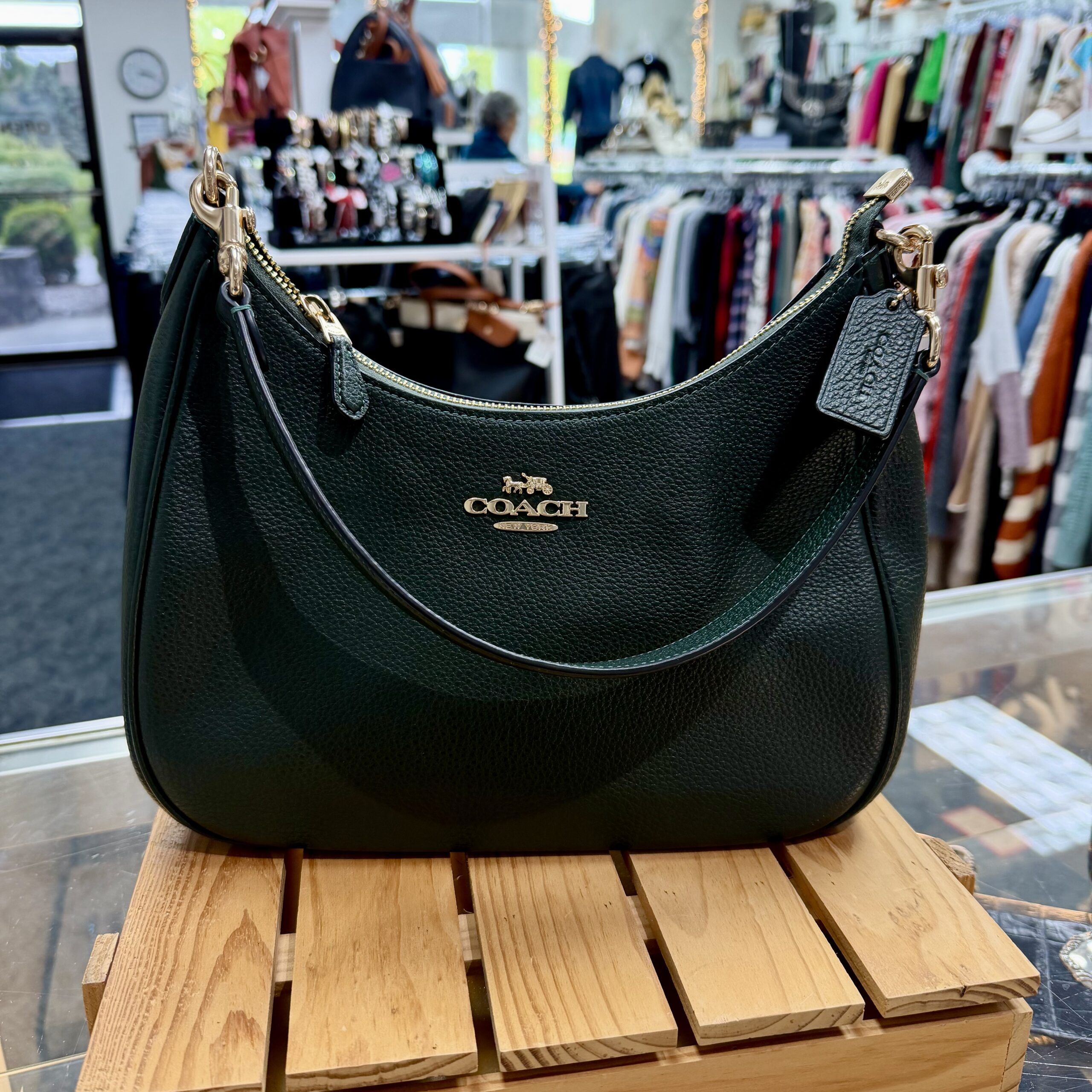 Authentic Coach green pebbled leather shoulder bag with gold-tone hardware and zip-top closure displayed in a women's consignment boutique.